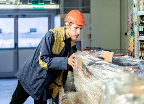 Male Worker loading various boxes of produce onto a pallet in a warehouse